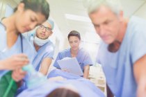 Chirurgen mit Klemmbrett schieben Patienten auf Trage im Krankenhausflur — Stockfoto