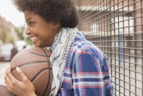Happy young woman holding basketball outdoors — Stock Photo