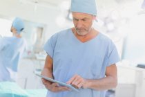 Мужской хирург с помощью цифрового планшета в операционной — стоковое фото