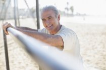 Portrait of senior man leaning on bar at beach — Stock Photo