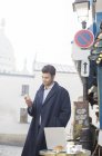 Бізнесмен використовує мобільний телефон у тротуарному кафе — стокове фото