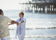 Entusiástico casal dançando na praia ensolarada — Fotografia de Stock