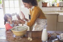 Щасливі гарні мати і дочка високої fiving на кухні — стокове фото