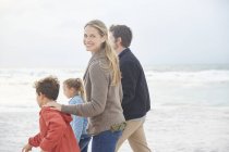 Портрет усміхненої сім'ї, що йде на зимовому пляжі — стокове фото