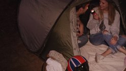 Casal jovem com lanterna dentro da barraca de acampamento — Fotografia de Stock