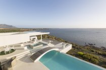 Sunny, tranquilla casa di lusso moderna vetrina esterna con piscina a sfioro e vista sull'oceano — Foto stock
