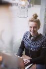 Портрет улыбающейся молодой женщины с ноутбуком в витрине кафе — стоковое фото