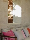 Каменная стена за скамейкой в патио с подушками — стоковое фото
