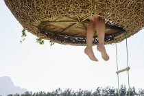 Pies de mujer colgando de la casa del árbol del nido - foto de stock