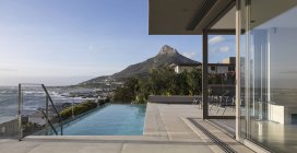 Vista sulle montagne e sull'oceano oltre la piscina sul giro fuori casa di lusso vetrina esterna — Foto stock
