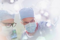 Cirujanos con máscara quirúrgica mirando hacia abajo en quirófano - foto de stock