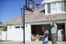 Abuelo y nieto jugando baloncesto en la entrada - foto de stock