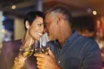Affectionate couple toasting white wine glasses in bar — Stock Photo