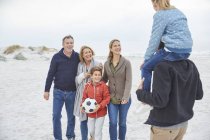 Família de várias gerações com bola de futebol na praia de inverno — Fotografia de Stock