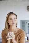 Gelassene Frau trinkt Kaffee und schaut auf der Terrasse weg — Stockfoto