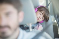 Girl with headphones sleeping in back seat of car — Stock Photo
