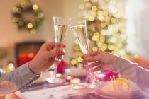 Casal tostando flautas de champanhe na mesa de jantar de Natal — Fotografia de Stock