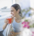 Smiling brunette woman in pajamas drinking juice — Stock Photo
