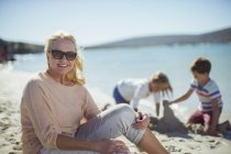 Літня жінка сидить на пляжі з сім'єю — стокове фото