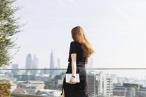 Mujer de negocios con tableta digital caminando en balcón urbano - foto de stock