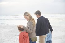 Sonriente familia caminando en la playa de invierno - foto de stock