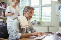 Son distracting father at work in home office — Stock Photo