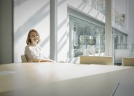 Portrait smiling businesswoman in sunny conference room — Stock Photo