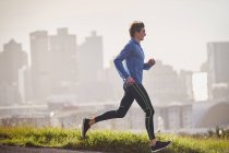 Corredor masculino corriendo en la soleada calle urbana - foto de stock