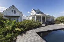 Soleado blanco moderno hogar escaparate exterior más allá de la piscina - foto de stock