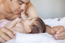 Father admiring adorable baby girl on bed — Stock Photo