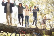 Enthusiastic family jumping from fallen log over bicycles — Stock Photo