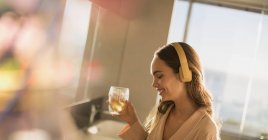 Smiling woman with headphones listening to music and drinking — Stock Photo