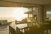 Pôr do sol vista para além do moderno pátio de vitrine em casa de luxo — Fotografia de Stock