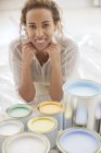 Mujer sentada frente a latas de pintura - foto de stock