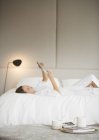 Frau im Bademantel liegt mit digitalem Tablet auf Bett — Stockfoto