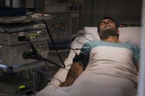 Пацієнт лежить у ліжку, прикріплений до обладнання моніторингу в реанімаційному відділенні — стокове фото