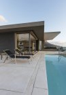 Стільці для відпочинку на колінах басейн за межами сучасного розкішного будинку вітрина екстер'єру — стокове фото
