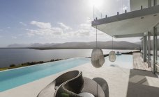 Sunny modern luxury home showcase exterior with infinity pool and ocean view — Stock Photo