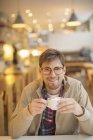Heureux jeune homme buvant du café dans le café — Photo de stock