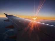 Pôr do sol atrás da asa do avião no céu — Fotografia de Stock