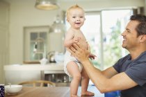 Father helping baby walk on table — Stock Photo