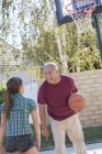 Grandfather and granddaughter playing basketball in driveway — Stock Photo