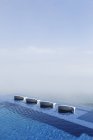 Cadeiras de gramado na piscina infinita com vista para o oceano — Fotografia de Stock