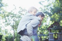 Father carrying son piggyback outdoors — Stock Photo