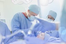 Cirurgiões operando em paciente do sexo feminino na sala de cirurgia — Fotografia de Stock