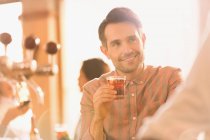 Усміхнений чоловік п'є коктейль у барі — стокове фото