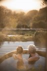 Sereno casal afetuoso imersão em banheira de hidromassagem no pátio com vista para o outono — Fotografia de Stock