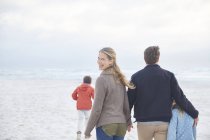 Retrato familia feliz caminando en la playa de invierno - foto de stock