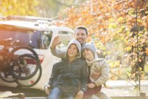 Pai e filhos tomando selfie no parque de outono — Fotografia de Stock