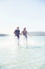 Casal espirrando na água na praia — Fotografia de Stock